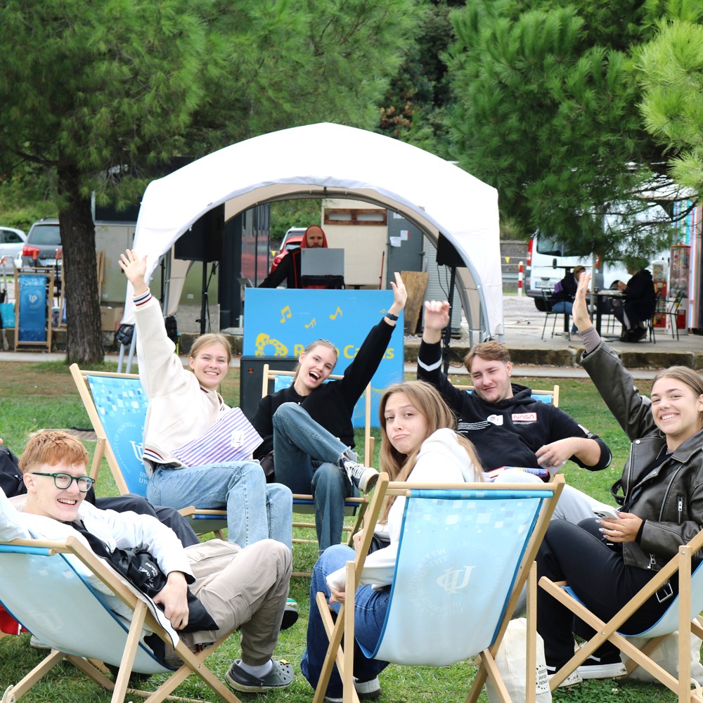 a group of people spending time together outdoors, waving to the photographer