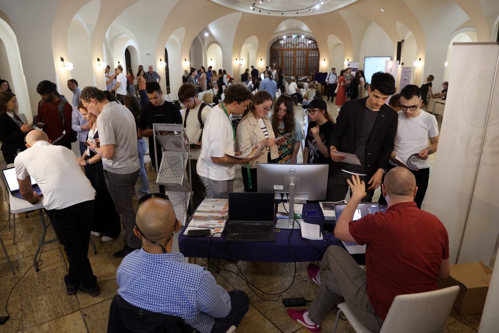 A group of people and a computer station in the foreground