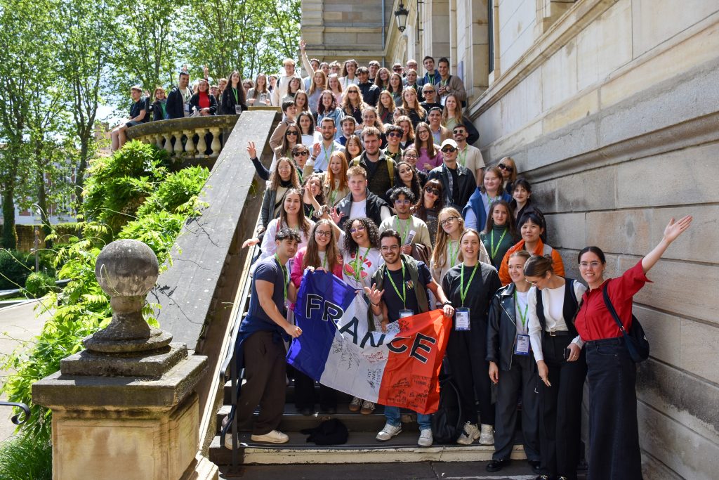 T4EU week participants posing for a photo on a set of stair holding a French flag
