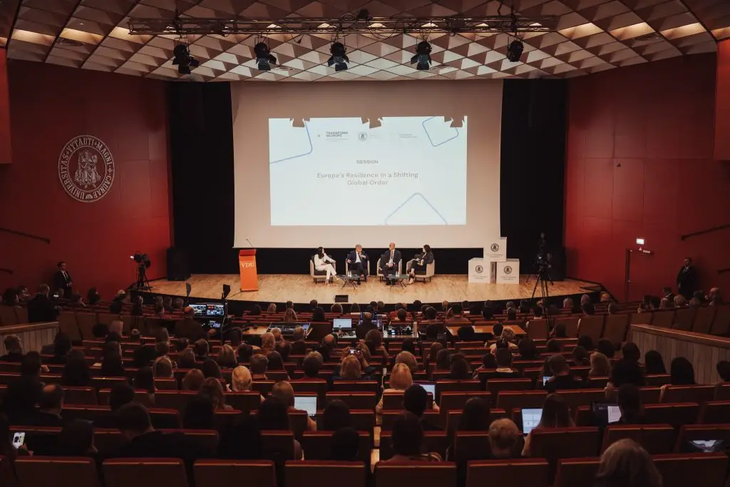A group of people sitting on a stage in front of a screen.