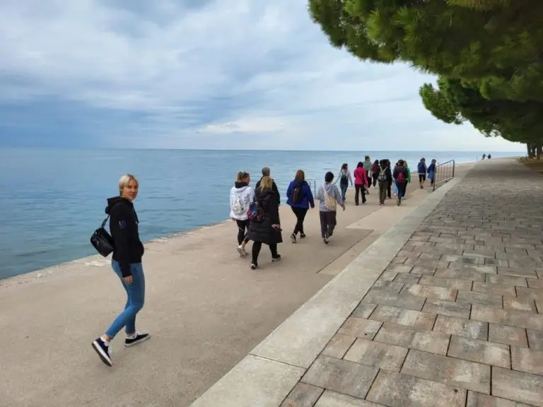 A group of people walking along a sidewalk by the water. Photo: University of Primorska