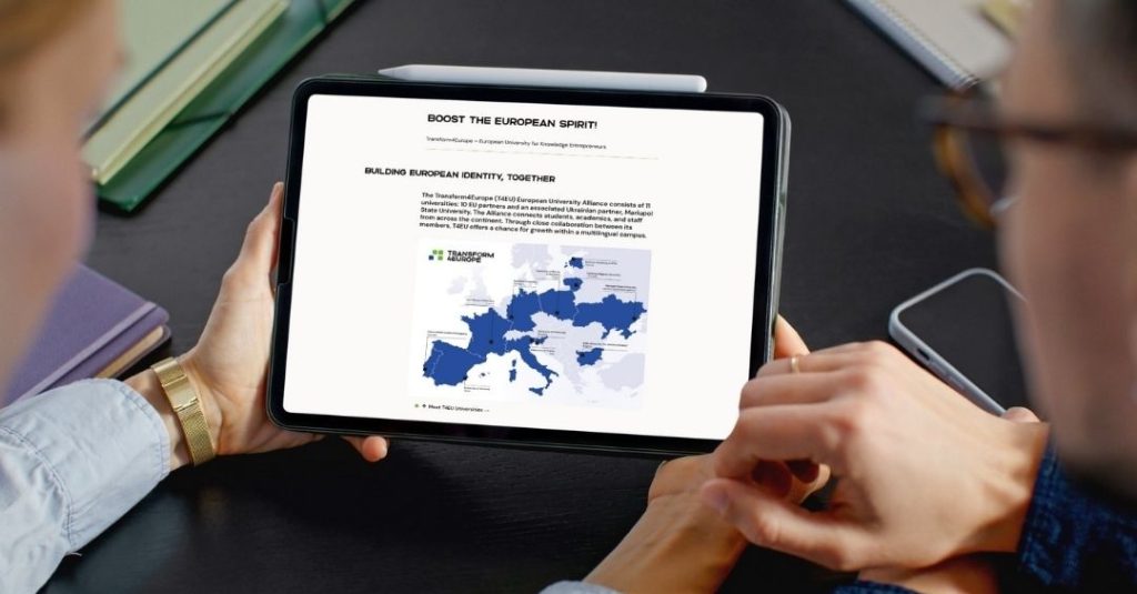 Two people hold and read a tablet displaying a webpage titled BOOST THE EUROPEAN SPIRIT! featuring a map of Europe with highlighted countries and a logo for the European University initiative.