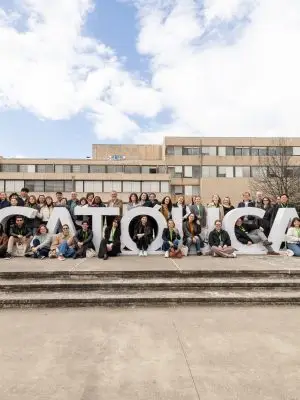 A large group of people posing for a photo at a large "Catolica" sign