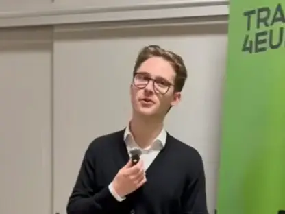 A young person wearing glasses, a white shirt, and a dark cardigan stands indoors holding a microphone. A green banner with partially visible text is on the right side of the image.