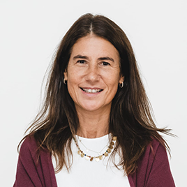 Woman with long brown hair, wearing a maroon cardigan, white top, and gold necklace, smiling against a plain white background.